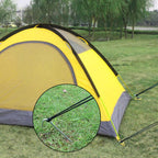 Securing a canopy leg to the ground using a 9-inch metal tent stake in sandy soil at a campsite