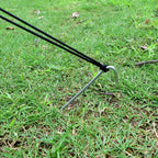 Set of 9-inch heavy duty galvanized steel tent stakes with hooked tops and sharp points, lying on grass